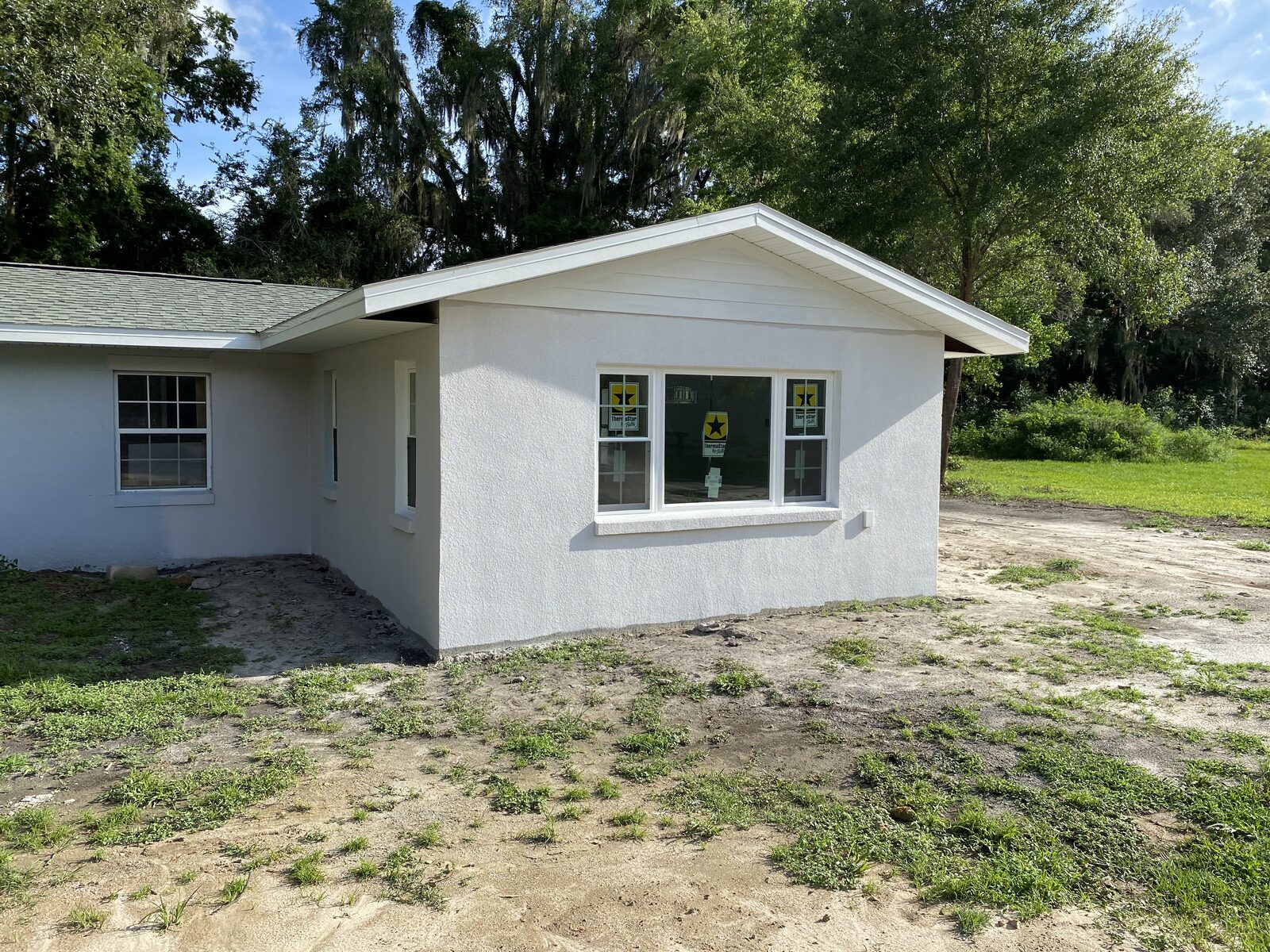 A finished single-storey house with new white stucco, new windows and a new roof